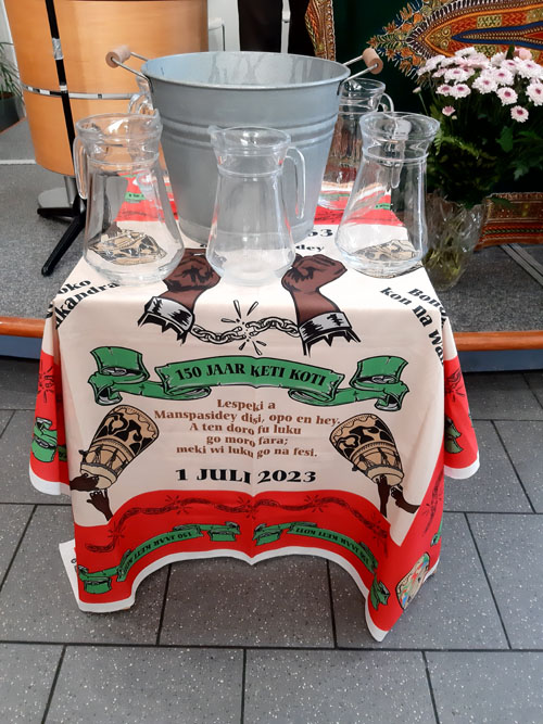 In De Nieuwe Stad Zuidoost tijdens kerkdienst tafeltje met speciaal ontworpen hoofddoek en water gegoten als teken van verbinding met de voorouders.